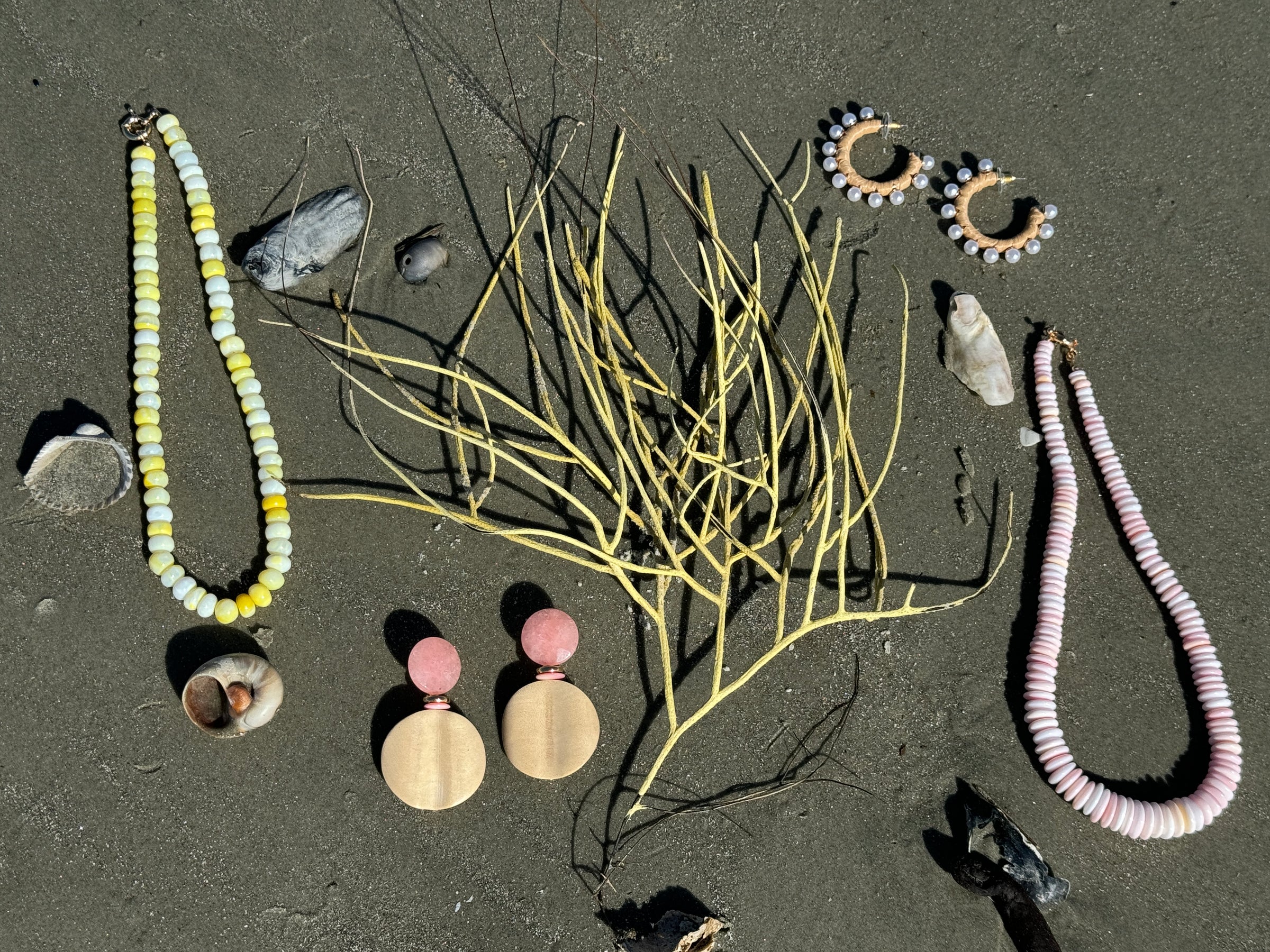 yellow opal necklace with wood and pink agate earring and pink queen conch statement necklace on the beach