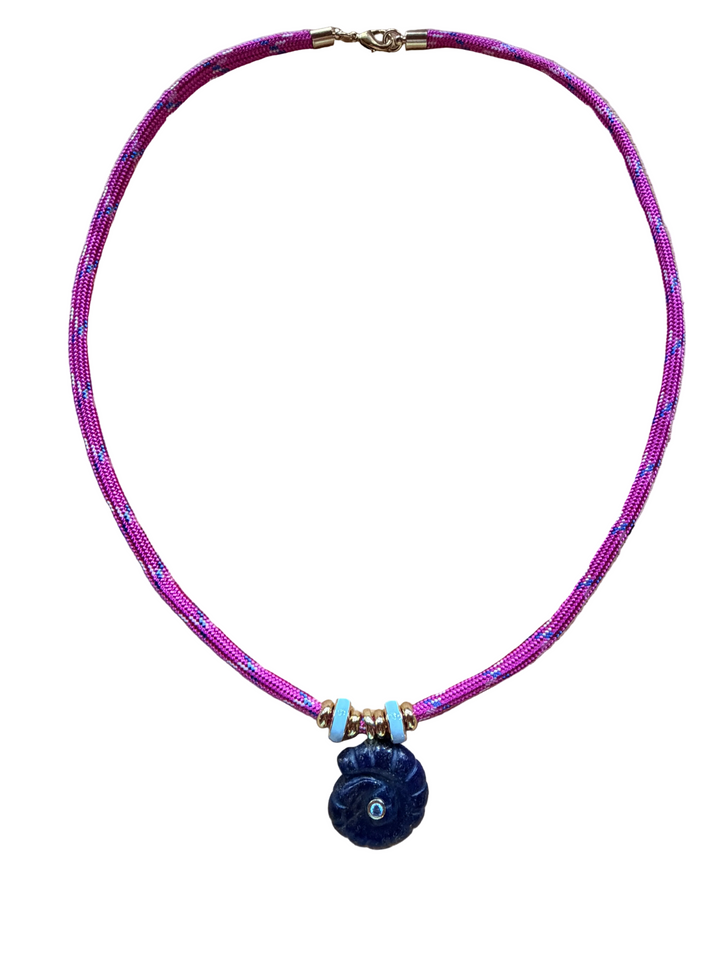 A beaded necklace featuring a vibrant magenta-pink and purple woven cord, accented with small gold-toned beads, light blue spacer beads, and a dark blue spiral shell pendant with a turquoise center.