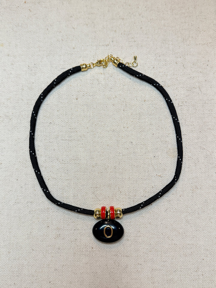 Black Oval Pendant with Red Spacers on a Black Cord Necklace