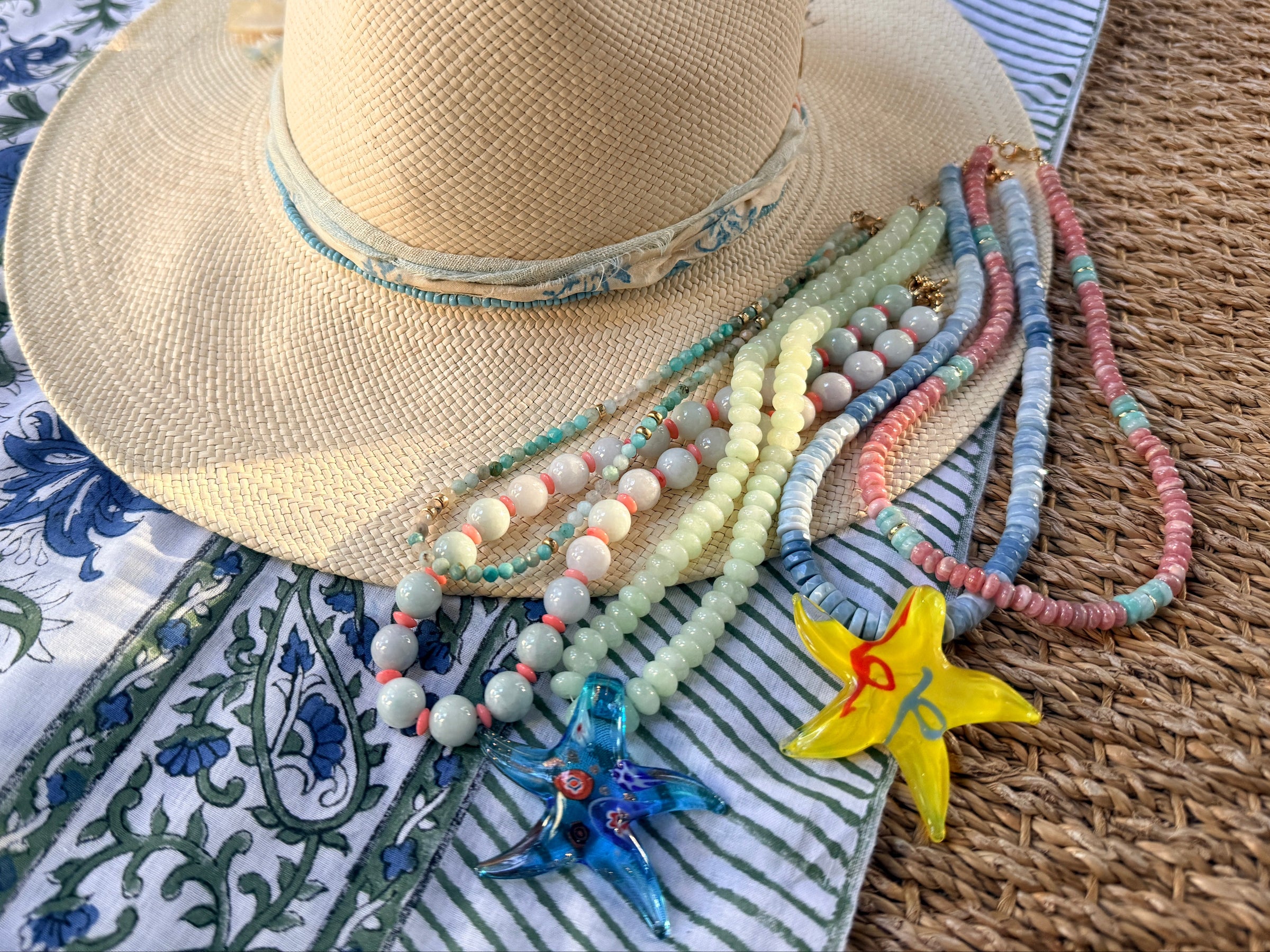 Straw hat with colorful beads and a starfish on a textured surface